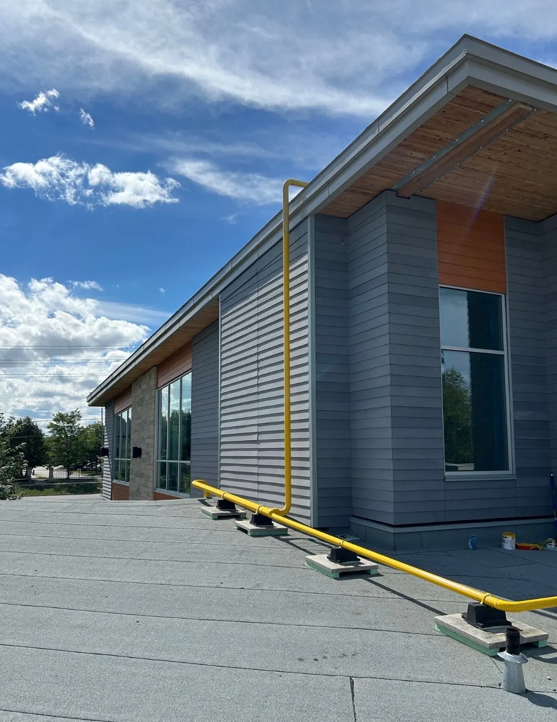 Yellow natural gas line on supports running across a commercial flat roof and up the building wall